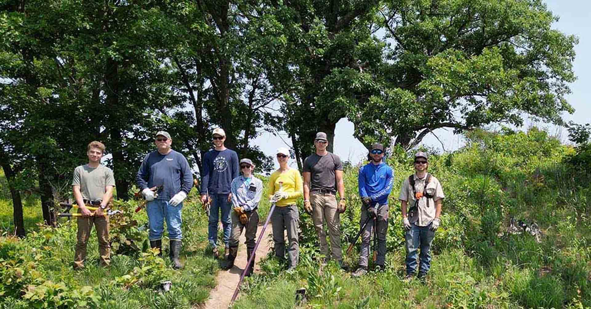 A group of volunteers standing together on a green hillside