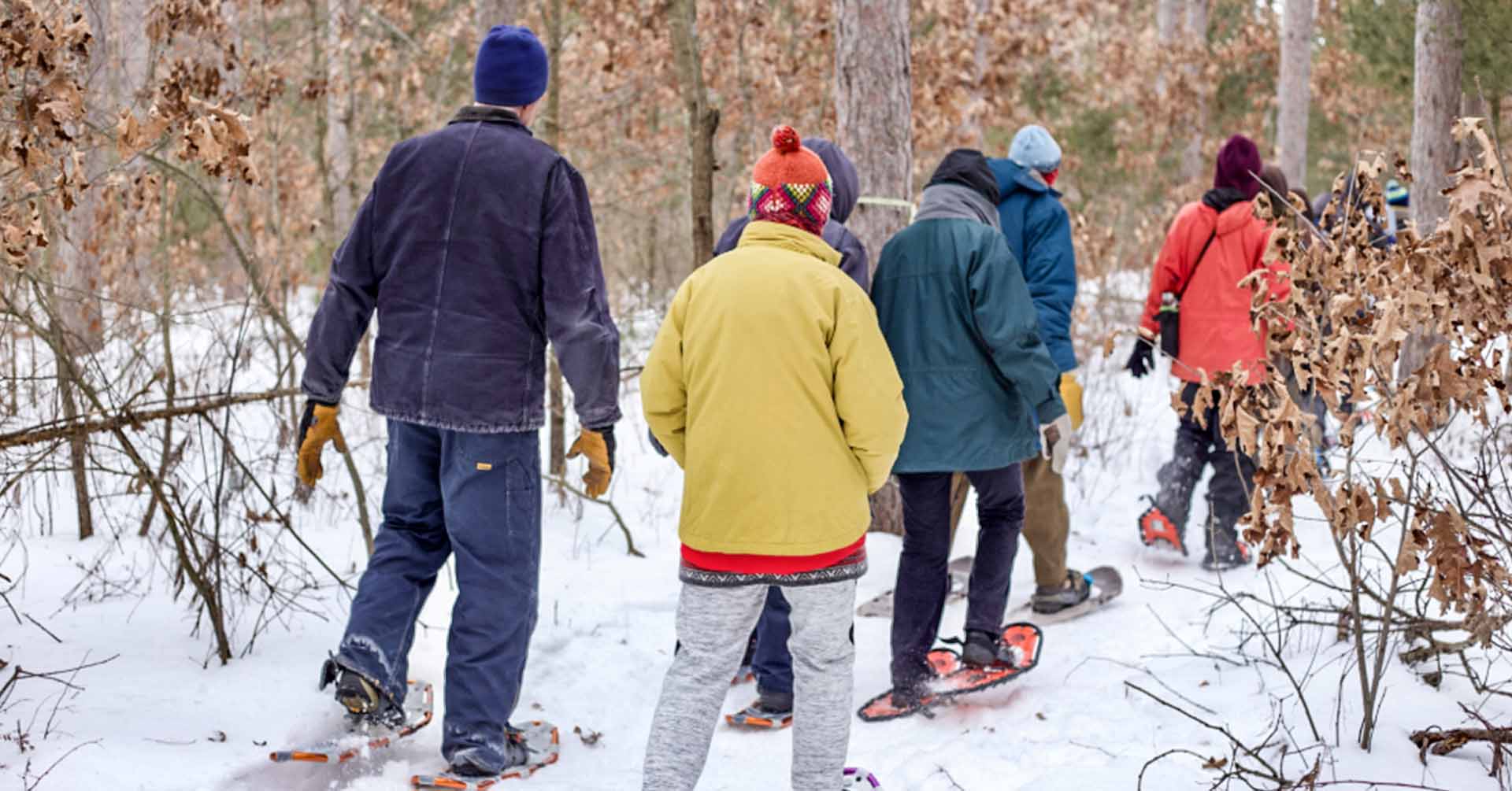 A group of people snowshoeing on a trail.