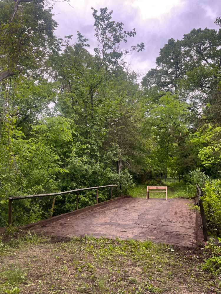 Trail leading over an old rustic bridge with iron railings.